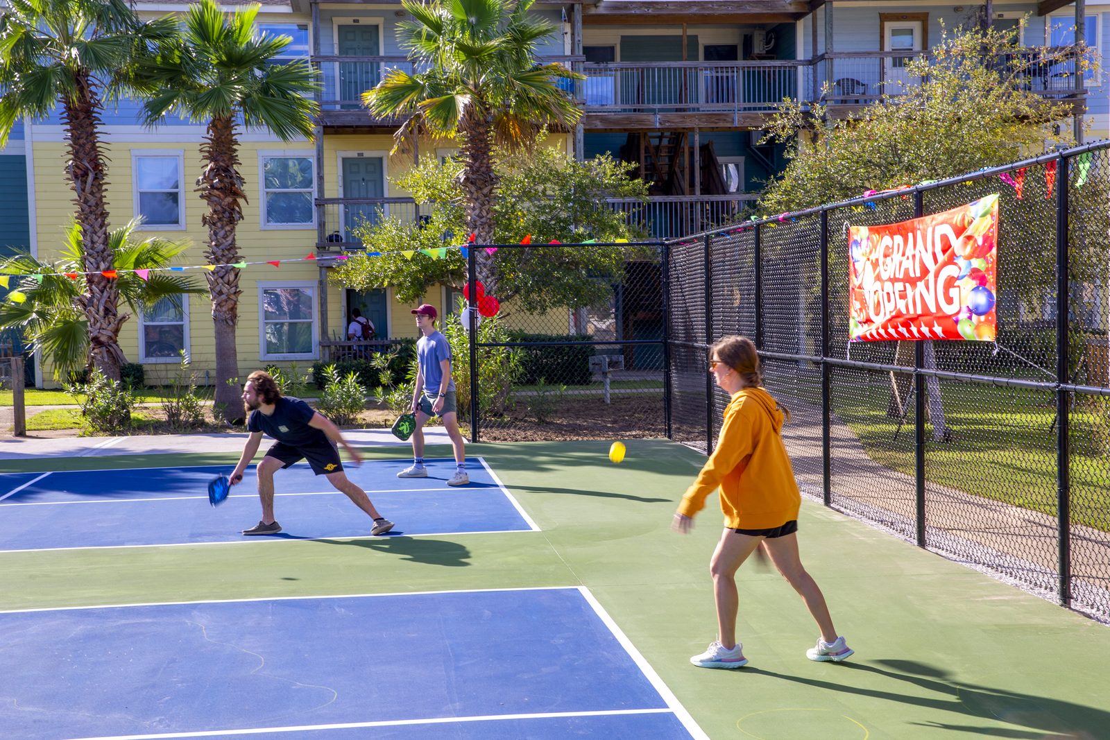 Residents playing pickleball on the blue UAG court